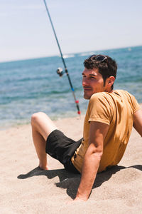 Man sitting with fishing rod at beach