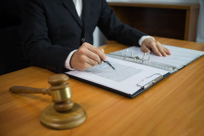 Midsection of man holding paper while sitting on table