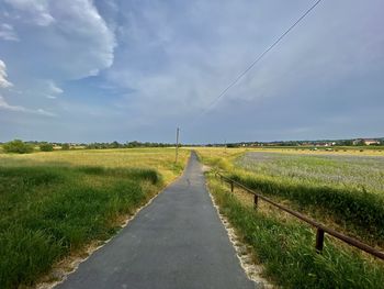 Road amidst field against sky