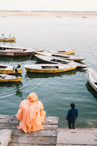 Rear view of men sitting on boat in lake