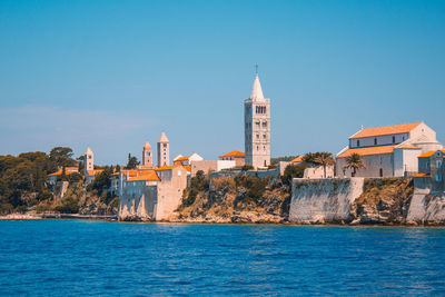 Buildings at waterfront against blue sky