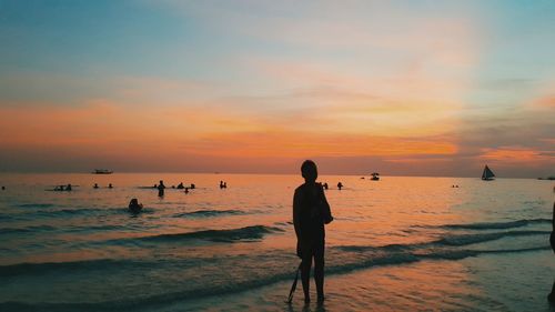 Silhouette man photographing sea against sky during sunset
