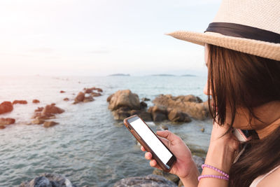 Man using mobile phone at beach against sky