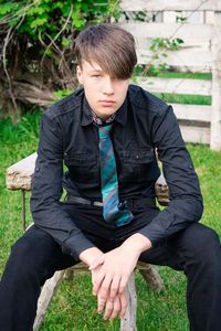 Portrait of teenage boy sitting on wooden stool at back yard