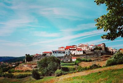 Houses by trees and buildings against sky