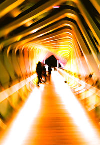 Silhouette people walking in illuminated tunnel