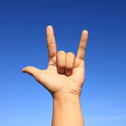 Close-up of human hand against clear blue sky