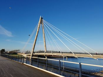 Low angle view of suspension bridge against blue sky