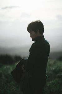 Side view of woman standing against sky