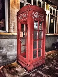 Red telephone booth against building in city