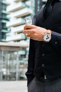 Midsection of man holding ice cream standing outdoors