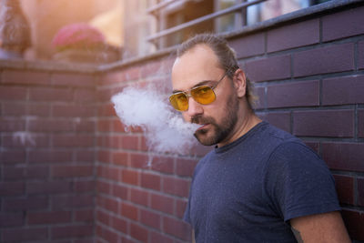 Portrait of man smoking against wall