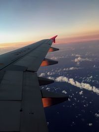 Airplane wing against sky during sunset