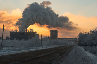 Road by factory against sky during winter