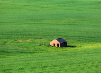 House on green field against sky