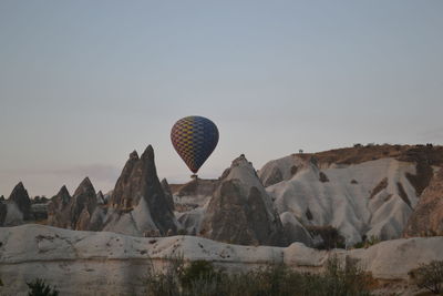 Hot air balloon flying over rocks against clear sky