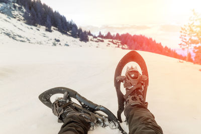 Low section of person on snowcapped mountain against sky