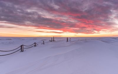 Scenic view of snow covered land against sky during sunset