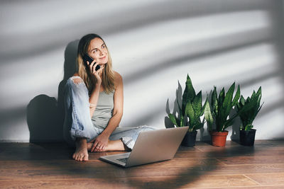 Smiling woman talking on phone while sitting at home