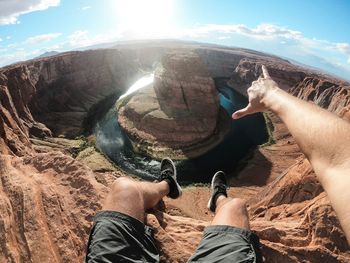 Low section of man gesturing against horseshoe bend