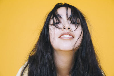 Close-up portrait of playful girl against yellow background