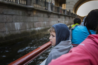 Boy looking away while standing by canal