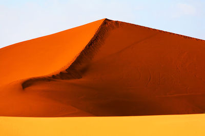 Low angle view of sand dunes against clear sky