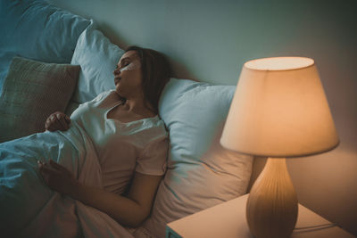 Midsection of woman lying down on bed at home