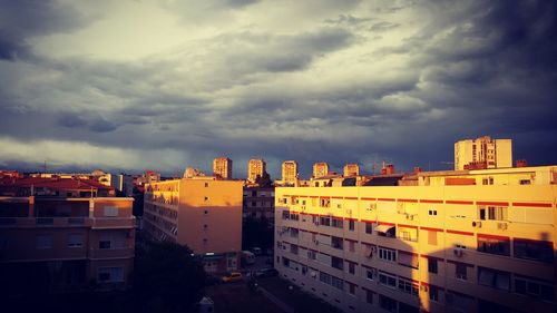 Buildings in city against cloudy sky