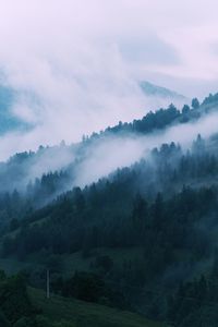 Scenic view of foggy mountain landscape against cloudy sky