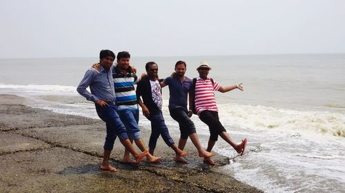 People standing on beach against sea against sky