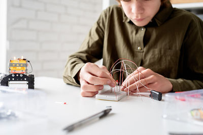 Boy in green shirt working with led lights on experimental board for science project