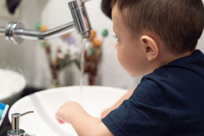 Close-up of boy washing hands in sink