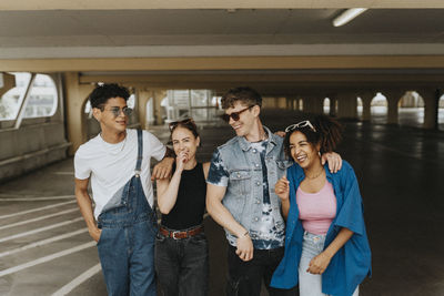 Cheerful fashionable male and female friends standing in parking garage