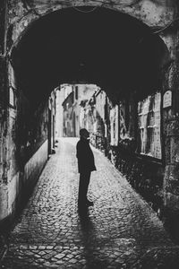 Rear view of man walking on footpath amidst buildings