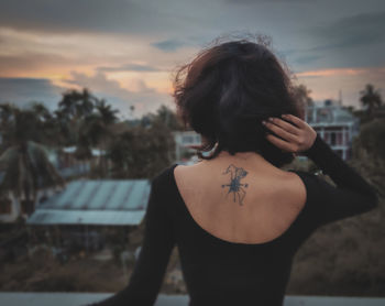 Rear view of woman looking at city during sunset