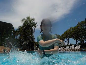 Portrait of girl splashing water in swimming pool
