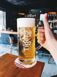 Midsection of woman holding beer glass on table