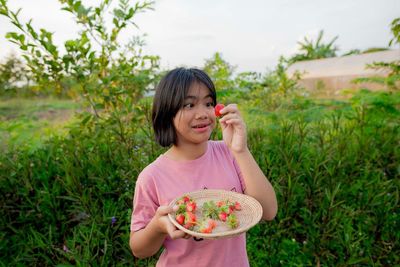 Young woman holding ice cream cone on field