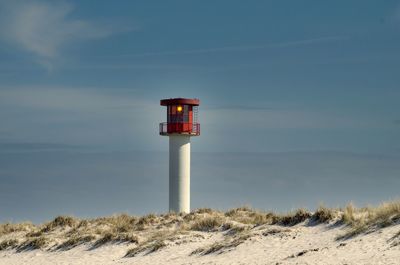 Lighthouse at beach against sky