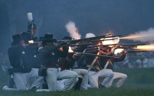 Rear view of people photographing against sky