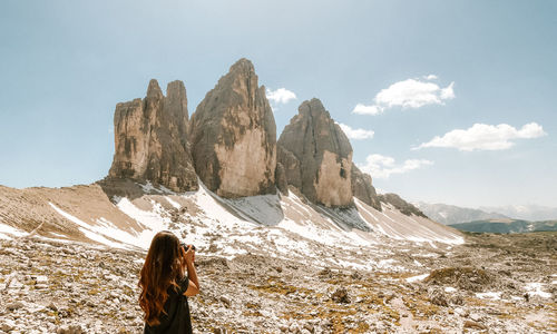 Rear view of woman photographing mountain range 