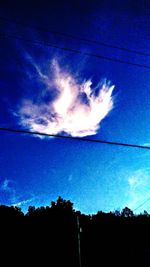 Low angle view of silhouette trees against blue sky