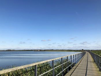 Bridge over calm blue sea against sky