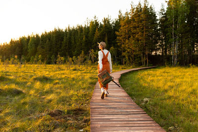 Woman botanist on ecological hiking trail. naturalist exploring wildlife ecotourism walking on path
