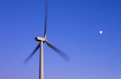 Wind turbine against blue sky and moon