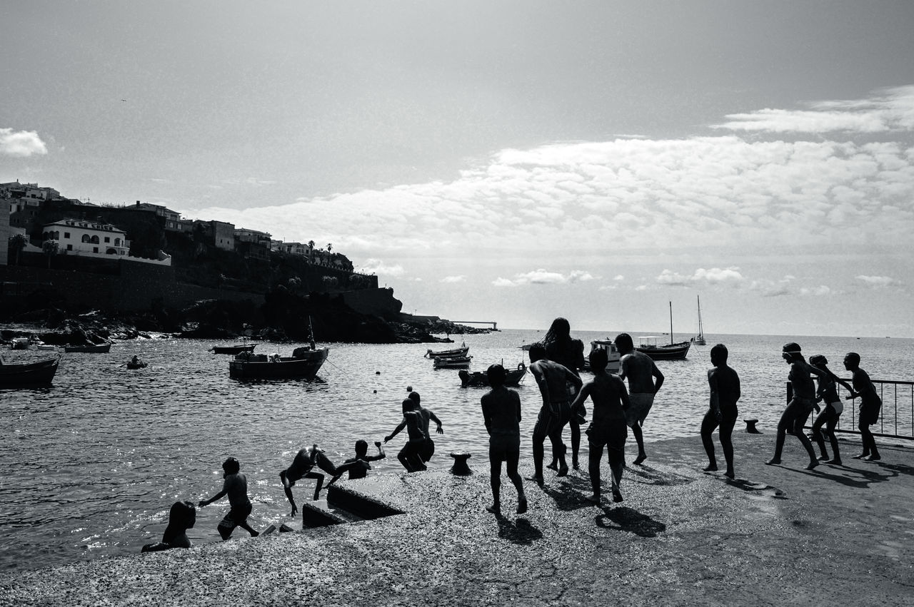 group of people, sea, beach, water, sky, black and white, land, monochrome, black, monochrome photography, nature, cloud, crowd, large group of people, leisure activity, men, holiday, trip, vacation, sports, coast, white, lifestyles, adult, women, ocean, day, person, sand, outdoors, enjoyment, beauty in nature