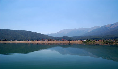 Scenic view of lake and mountains against clear blue sky