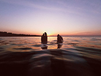 Rear view of silhouette people on beach against sky during sunset