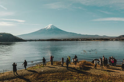 People on beach by lake against sky